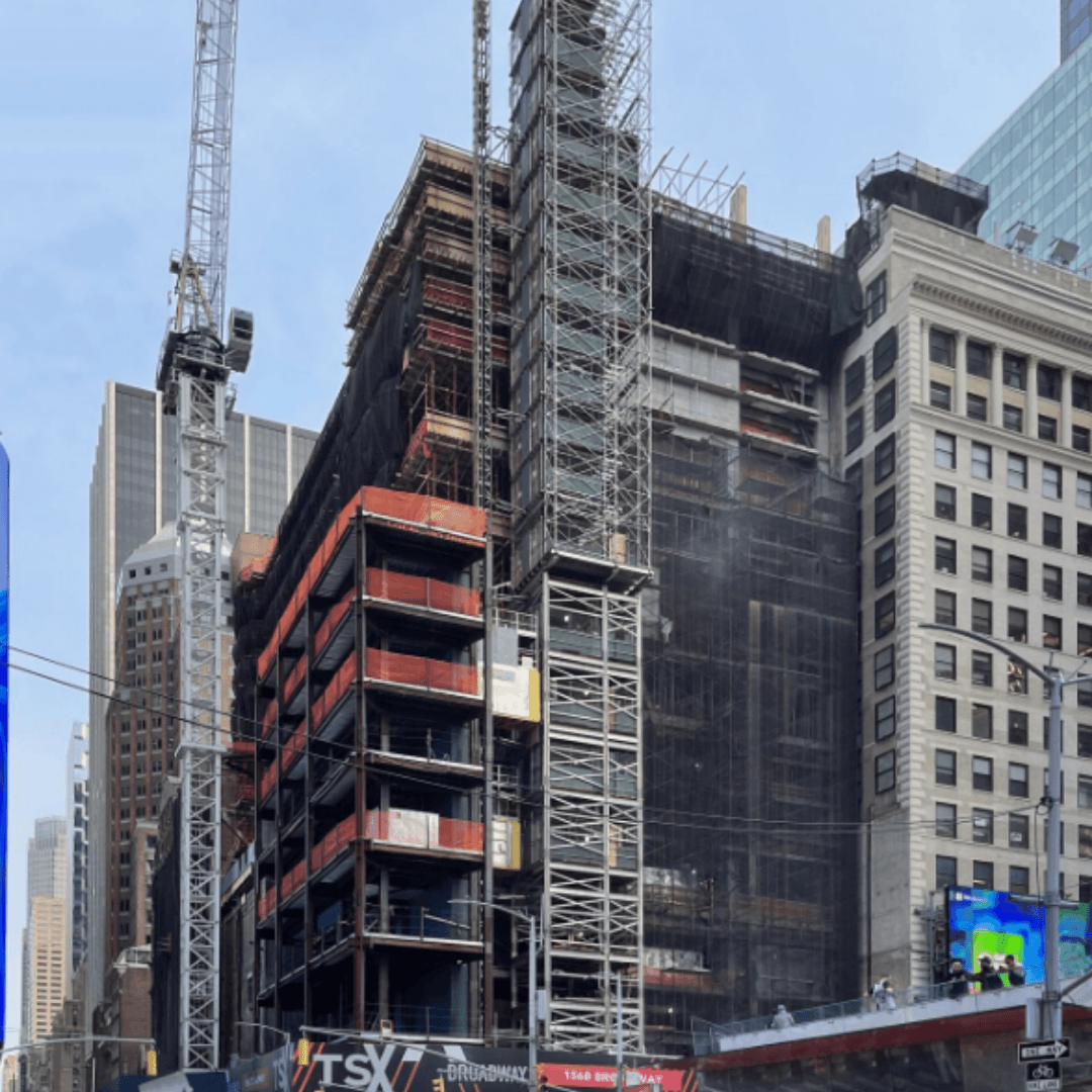 Street level point of view of the TSX Broadway under construction with scaffolding and cranes.